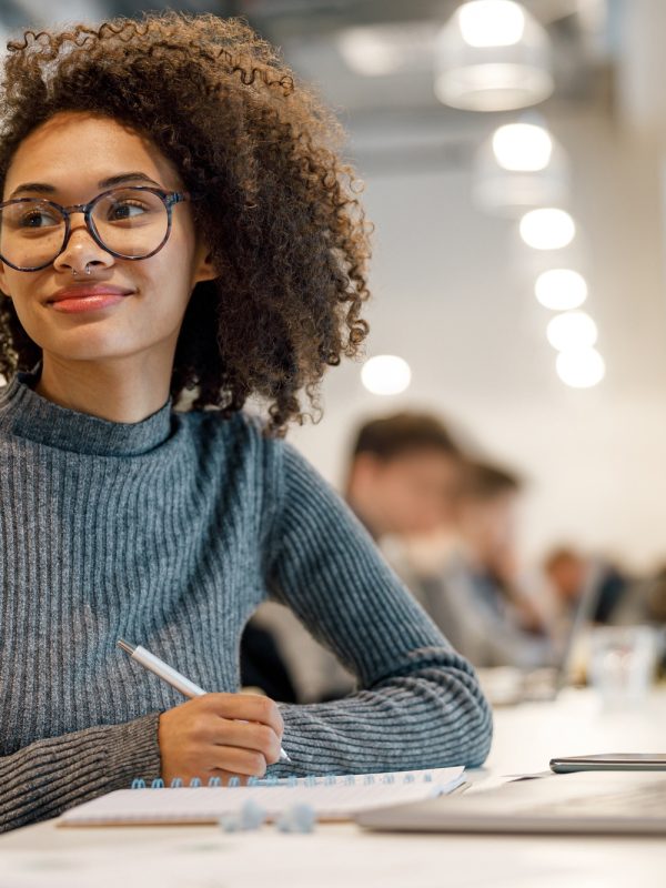 Smiling afro american woman student studying online while sitting in cozy cafe